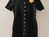 une robe noire et blanche accrochée au mur à côté d'un cintre
