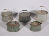 several old metal buckets are lined up on a white surface