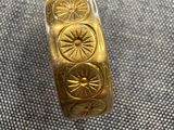 un gros plan d'une bague en or ornée d'un motif représentant un soleil