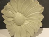 a white vase with a flower on it sitting on a table