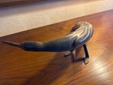 sculpture représentant un oiseau posée sur une table en bois, avec un miroir en arrière-plan