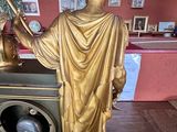 a gold statue of a man holding a clock