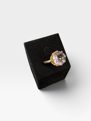 un gros plan d'une bague posée sur une boîte noire, sur une surface blanche