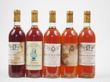 six bouteilles de vin sont alignées sur une surface blanche