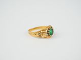 a gold ring with a green stone in the center