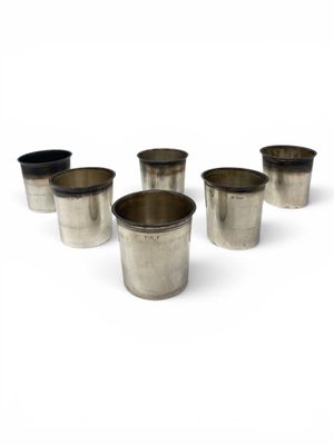six silver cups are lined up in a row on a white surface