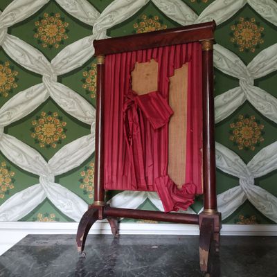 une chaise rouge recouverte d'un rideau rouge, placée devant un mur recouvert de papier peint vert