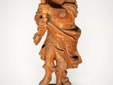 an old wooden statue of a man holding a torch in his hand