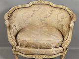 une chaise ancienne dont le dossier est recouvert d'un tissu à motifs floraux et l'assise d'un tissu doré