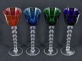 quatre verres à vin de couleurs différentes sont alignés sur un fond noir