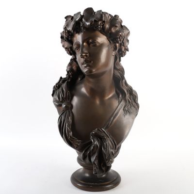 a bronze bust of a woman with flowers on her head