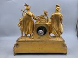 a gold clock with three figures on top of it