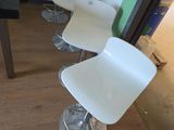 Plusieurs chaises blanches sont alignées en rang devant un mur vert.