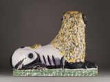 a ceramic sculpture of a panda laying down on the ground