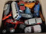 many toy cars in a cardboard box on the floor