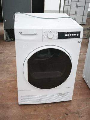 une machine à laver blanche posée à même le sol dans une pièce