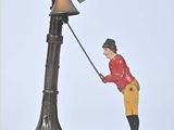 figurine of a man holding a pole with a bird on top of it