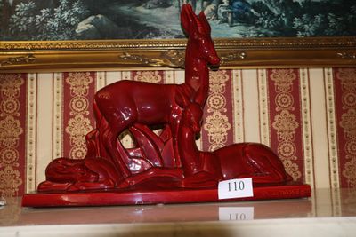une statue rouge représentant un cerf, exposée devant un tableau