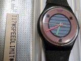 une montre noire avec un cadran rose et une trotteuse verte