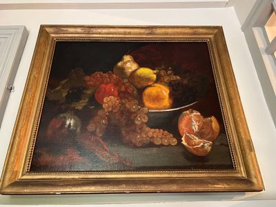 un tableau accroché au mur d'une pièce où se trouve un bol de fruits sur la table