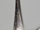 a silver spoon with a silver handle hanging from it