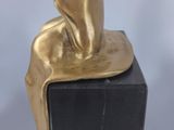 statue of a woman sitting on a black block with a white background
