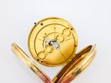 a gold pocket watch sitting on top of a white surface