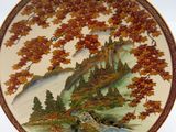 a plate with a painting of a mountain scene on it
