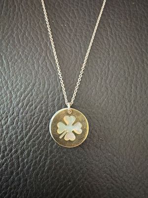 un collier orné d'un trèfle à quatre feuilles, posé sur une surface en cuir noir