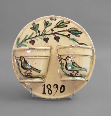 a ceramic plate with a bird on it and two cups on it