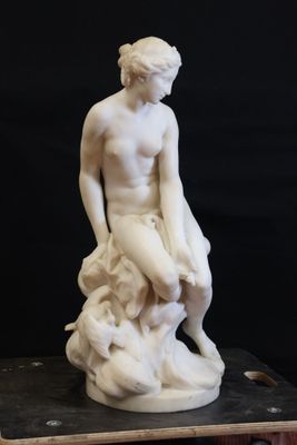 a white statue of a man sitting on top of a rock