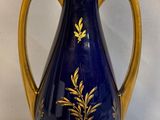 a blue vase with gold decoration on it sitting on a white surface