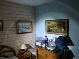 a bed and a dresser in a room with a painting on the wall
