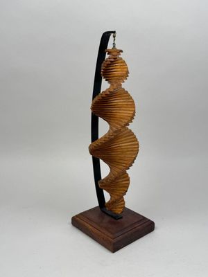 une photo représentant une sculpture en forme de spirale posée sur un socle en bois