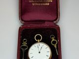 a box with a key and a pocket watch inside of it