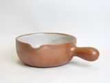 a small bowl with a wooden handle on a white surface