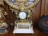 une horloge dorée posée sur une table en bois, à côté d'un vase