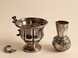 une coupe en argent et un vase en argent posés sur une table