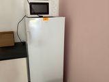 un réfrigérateur blanc et un micro-ondes dans une petite pièce