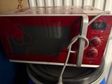 a red microwave sitting on top of a stack of plates