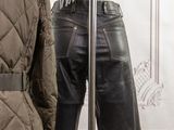 a mannequin in front of a coat and a jacket on a stand