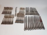 de nombreuses fourchettes et couteaux disposés sur la table
