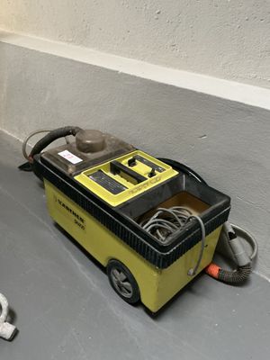 a black and white cat laying on the floor next to a yellow and black machine