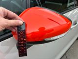 a person holding a measuring tape in front of a car