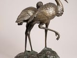 bronze statue of two birds standing on a rock on a white background