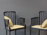 pair of black chairs with yellow cushions against a gray wall