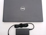 dell laptop with power cord and charger sitting on a white surface