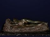 bronze statue of a woman laying on a rock on a blue background
