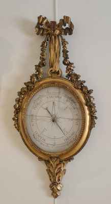 une horloge en or accrochée au mur, sur laquelle figure un cadran