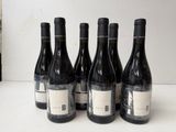 six bottles of wine are lined up on a counter